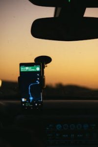Smartphone GPS navigation held in a car during a picturesque sunset drive. Ideal tech travel imagery.